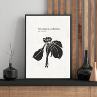 Framed artwork with a black and white flower illustration and text on a wall.