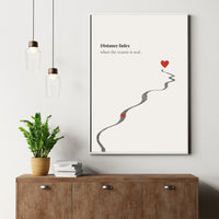Framed artwork with a heart and road illustration on a wall above a wooden cabinet.