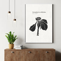 Framed artwork with a black and white floral design and text on a wall above a wooden cabinet.