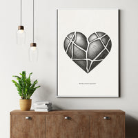 Framed artwork of a black heart design on a white wall above a wooden cabinet with a plant and books.