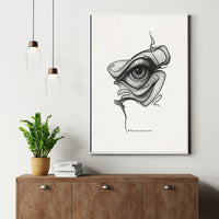 Framed artwork of an eye design on a wall above a wooden cabinet with a plant and books.