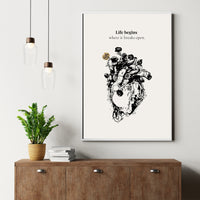 Framed artwork of a black and white heart with flowers on a wall above a wooden cabinet.