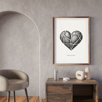 Framed artwork of a geometric heart on a wall above a wooden desk with decorative items.