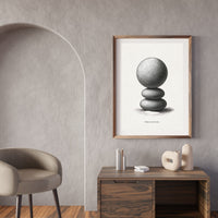 Framed artwork of stacked stones on a wall in a modern interior setting.