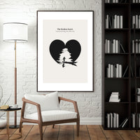 Framed artwork of a black heart with a tree inside, leaning against a white brick wall in a living room.