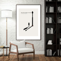 Framed artwork on a wall in a room with a chair, lamp, and bookshelf.