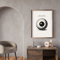 Framed artwork on a wall in a modern interior setting with a wooden desk and chair.