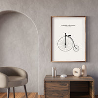 Framed poster with bicycle illustration on a wall in a modern interior setting.