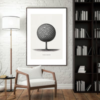 Framed black and white artwork of a tree on a wall in a room with a chair, lamp, and bookshelf.