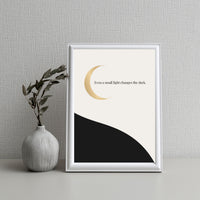 Framed artwork with a crescent moon and text on a plain background