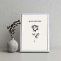Framed artwork with a rose illustration and text on a gray textured wall.