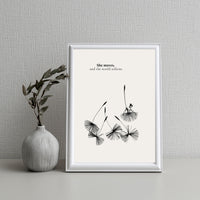 Framed artwork with black and white floral design and text on a gray wall.