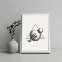 Framed black and white abstract art print on a gray wall with a vase and plant.