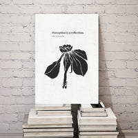 Canvas print with black silhouette of a flower and text on a stack of books against a white brick wall.