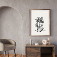 Minimalist black and white poster featuring a hand holding blooming flowers with the quote “Care creates what survives”