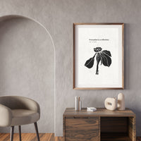 Framed artwork on a wall in a modern interior setting with a chair and table.