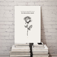 Canvas with a rose illustration and text on a stack of books against a white brick wall.