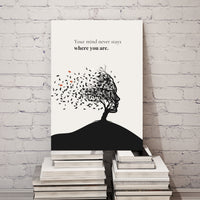 Canvas print with a tree-shaped person and text on a stack of books against a white brick wall.